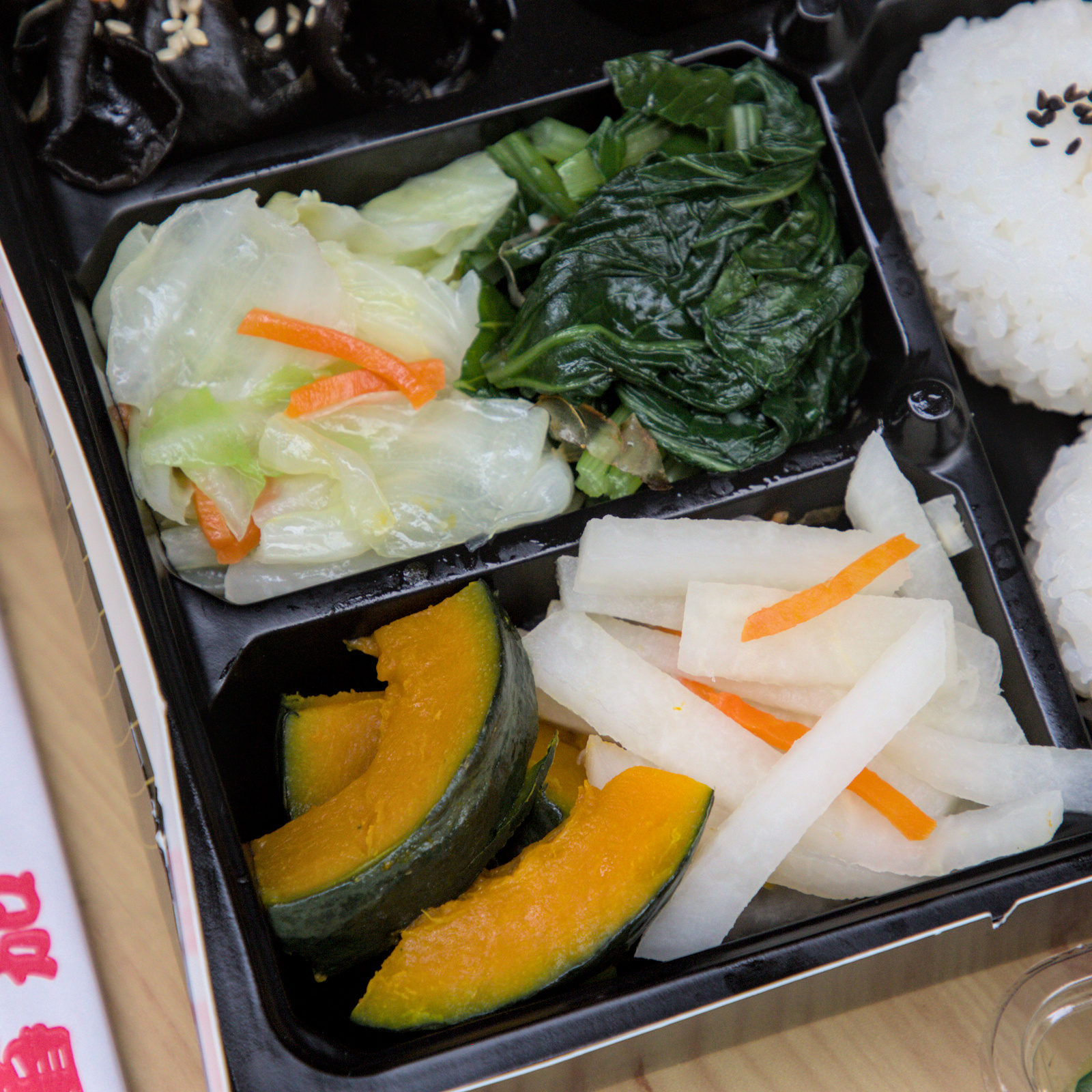 紅蕃茄客製化便當的美味配菜 紅蕃茄客製化便當中的配菜近照,包含滷豆干、爽脆的醃蘿蔔、清甜的烤南瓜,每一樣配菜都經過精心處理,色彩繽紛,讓便當更加豐富且健康。