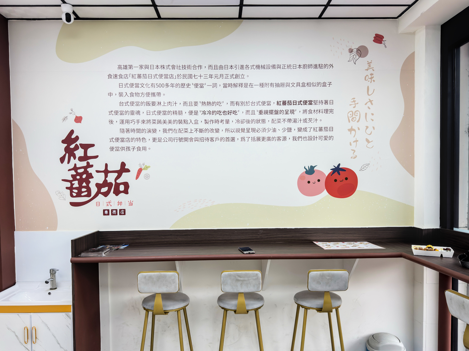 紅蕃茄日式便當專賣店牆面彩繪壁畫,介紹品牌理念 紅蕃茄日式便當店內牆面的大型彩繪壁畫,畫有可愛的紅蕃茄吉祥物與中、日文介紹,詳細闡述店家的創業理念與便當特色,將品牌精神與設計美學完美結合。