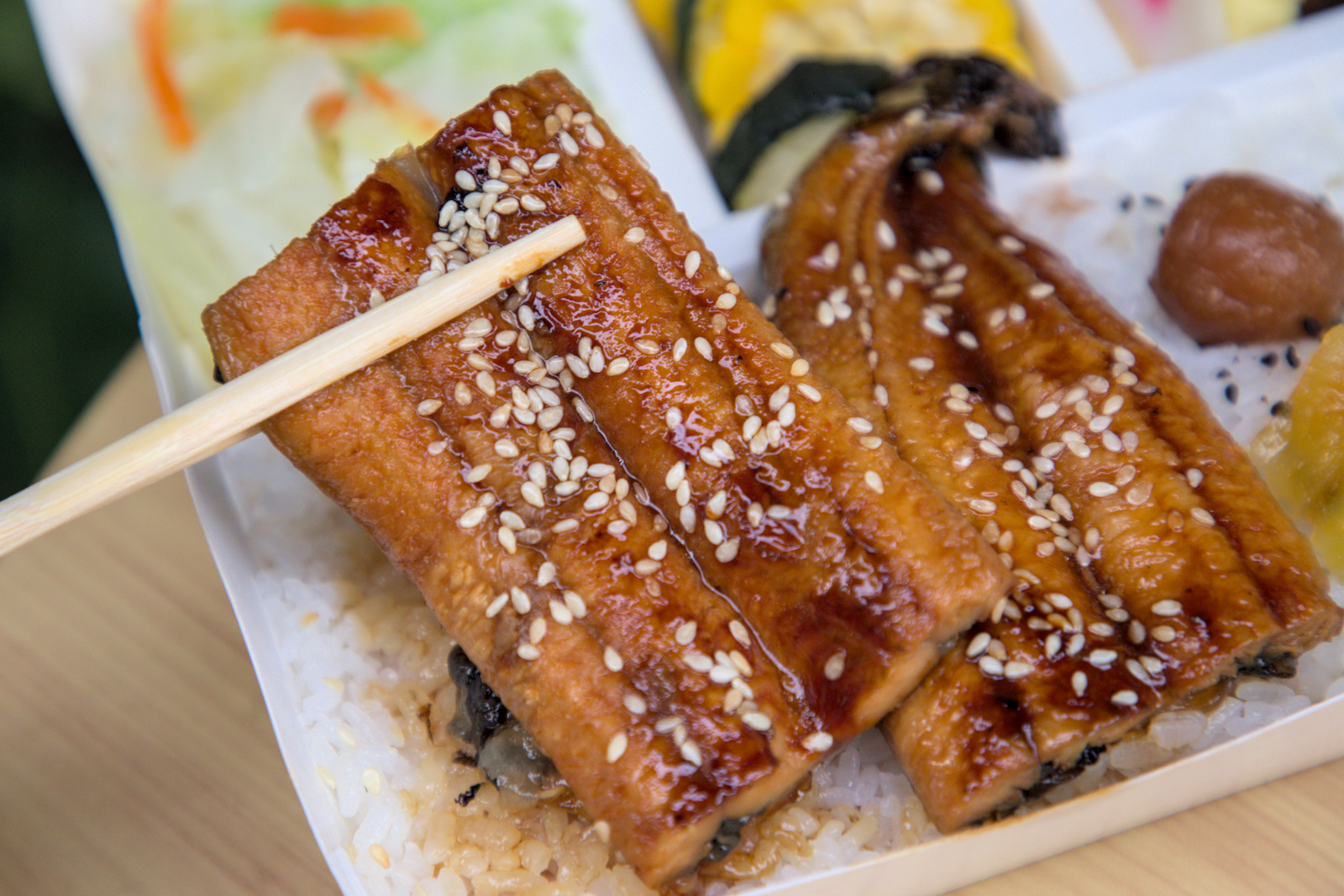 紅蕃茄鰻魚飯,焦香Q彈的蒲燒鰻魚 紅蕃茄鰻魚飯,蒲燒鰻魚的特寫,魚皮烤得焦香,魚肉Q彈緊實,表面覆蓋著濃郁醬汁和白芝麻,展現出絕佳的烹調工藝。