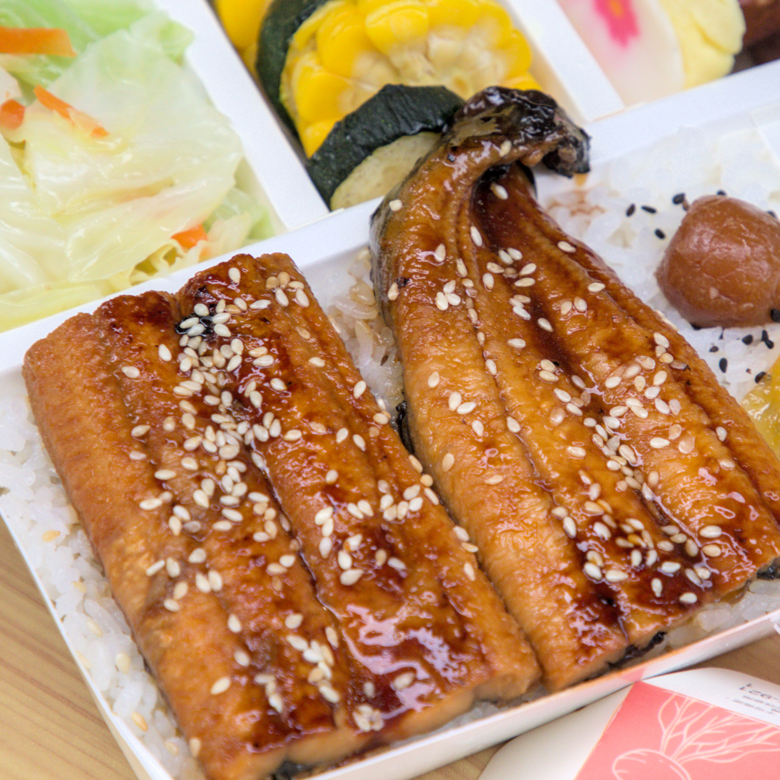 紅蕃茄鰻魚飯,蒲燒鰻魚的誘人色澤 紅蕃茄鰻魚飯的蒲燒鰻魚近照,淋上特製醬汁後金黃油亮,灑上白芝麻增添香氣,看起來美味可口,展現日式蒲燒料理的精髓。